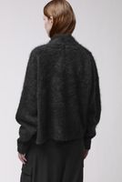 Frau trägt oversized schwarzen Wollmantel mit weitem Schnitt, schwarze Hose.