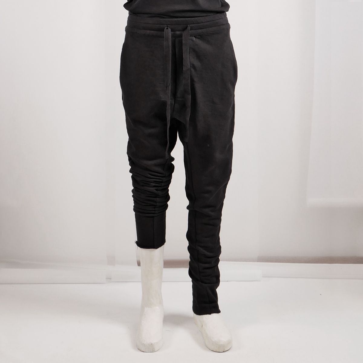 Schwarze, weite Jogginghose mit seitlichem Zugkordel, weiße Sneakers, schmale Beine.