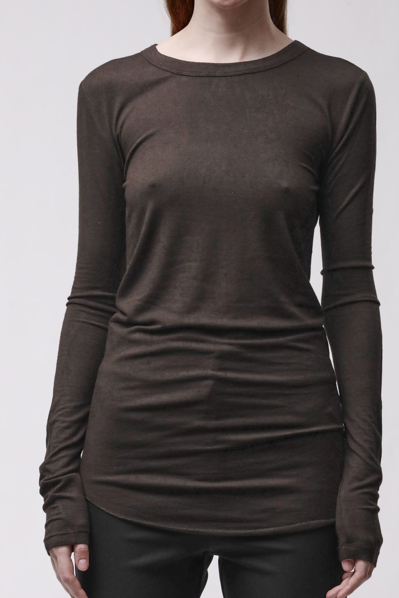 Frau trägt oversized schwarzes Langarm-Shirt und schwarze Leggings, seriöser Look.