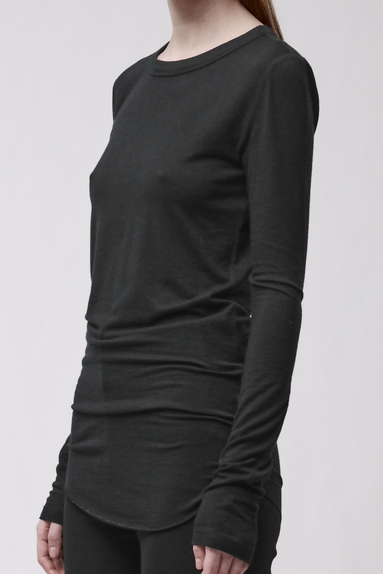 Frau trägt schwarzes langärmliges Shirt mit weitem Schnitt und schwarze Leggings.