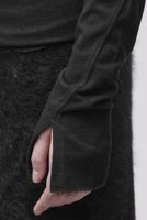 Person mit schwarzem oversized Pulli und flauschigem Rock, Hand an der Ärmelnaht.