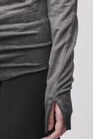 Person trägt grauen oversized Pullover mit schwarzen, weiten Hosen, Hand in Tasche.