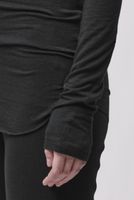Person trägt schwarzes langärmliges Shirt und schwarze Hose, Hand in Hosentasche.