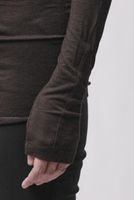 Person trägt schwarzen, figurbetonten Rollkragenpullover mit Textur, Hand zeigt auf Hose.