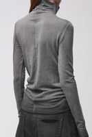 Frau trägt grauen oversized Rollkragenpulli mit schwarzen weiten Hosen, Rückansicht.