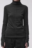 Frau trägt schlichtes schwarzes Turtleneck-Kleid mit weiten Ärmeln und flauschigen Hosen.
