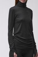 Frau trägt schlichtes, schwarzes Turtleneck-Kleid mit langen Ärmeln, seriös und elegant.