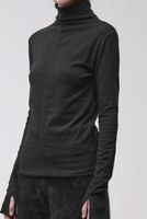 Frau trägt schwarzes Turtleneck-Kleid mit weitem Schnitt und texturierten Hosen, seriös-elegant.