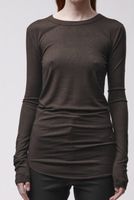 Frau trägt oversized schwarzes Langarm-Shirt und schwarze Leggings, seriöser Look.
