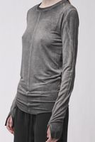Frau trägt graues langärmliges Shirt und schwarze weite Hose, seriöser Look.