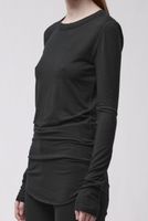 Frau trägt schwarzes langärmliges Shirt mit weitem Schnitt und schwarze Leggings.