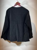 Schwarzes oversized Hemd mit weitem Schnitt, an Hanger hängend.