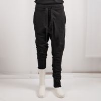 Schwarze, weite Jogginghose mit seitlichem Zugkordel, weiße Sneakers, schmale Beine.