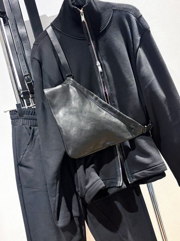 Schwarze Jogginghose mit oversized Pullover und grauer Lederumhängetasche.