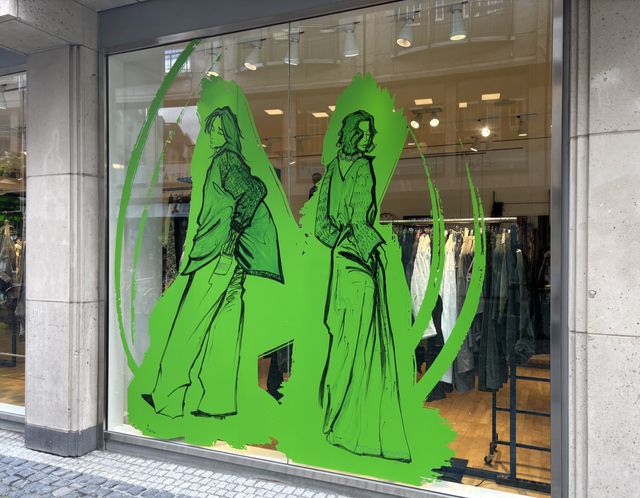 Modische Damenkleider in grüner Silhouette vor Schaufenster mit Innenansicht.