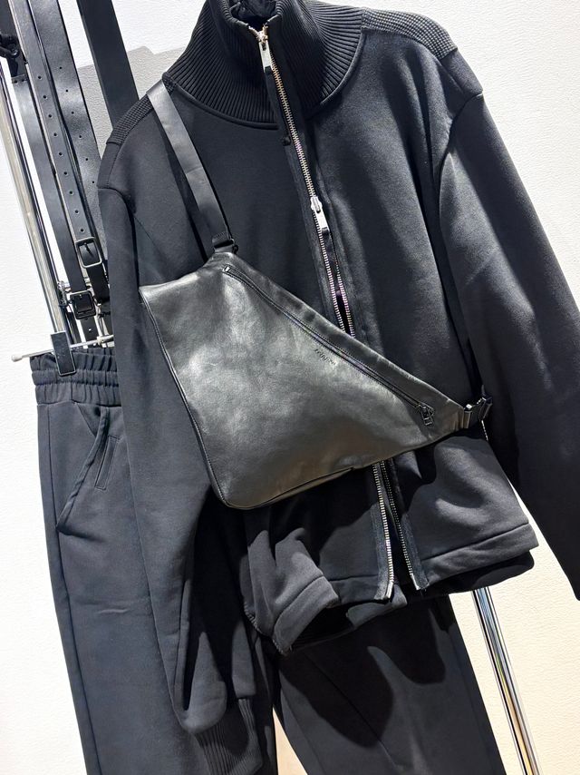 Schwarze Jogginghose mit oversized Pullover und grauer Lederumhängetasche.