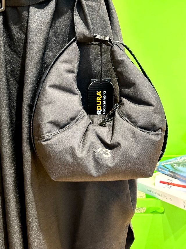 Schwarzer Dura-Tragebeutel mit Logo und schwarzem Verschlussband, hängend an Jacke.
