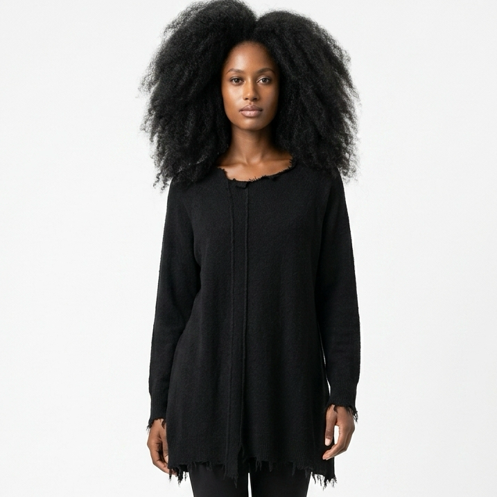 Schwarzes, langärmliges Überkleid mit Fransen, schwarze Pants und Stiefeletten, große Afro-Locken.
