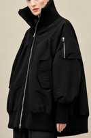 Schwarzer oversized Mantel mit hochgeschlagenem Kragen und Zipper-Pockets, elegant und modern.
