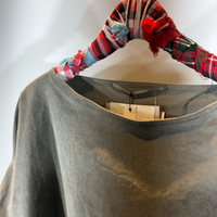 Graue Bluse mit Paspel-Aufschlag hängt an Bügel mit Preisetikett.