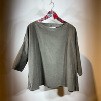 Graues oversized T-Shirt mit Rundausschnitt auf Holzklammern hängend.