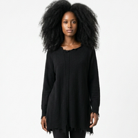 Schwarzes, langärmliges Überkleid mit Fransen, schwarze Pants und Stiefeletten, große Afro-Locken.
