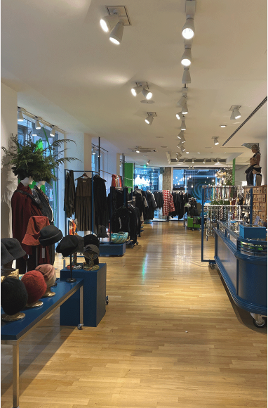 Moderne Boutique mit Kleidung, Accessoires und gut beleuchteten Regalen.