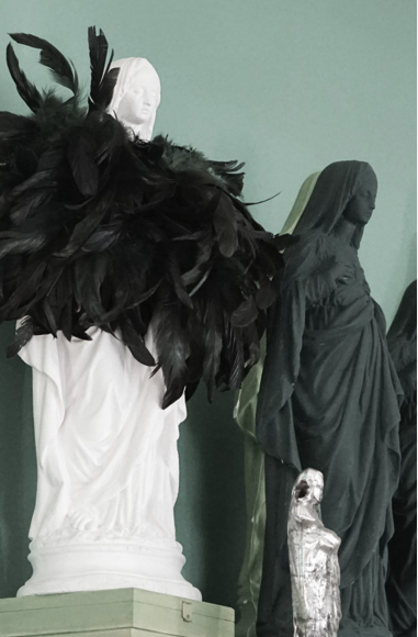 Kostümierte Statuen mit Federhaube und Gewand in Ausstellungsvitrine.