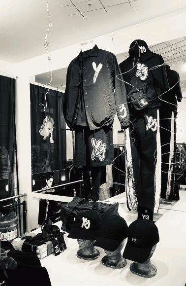 Schwarz-weißes Y3-Mode-Outfit mit Jacken, Hose und Accessoires in Vitrine.