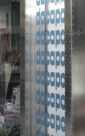 Moderne Metalltafel mit vertikaler „docapost“-Schriftzug-Reihe in Blau.