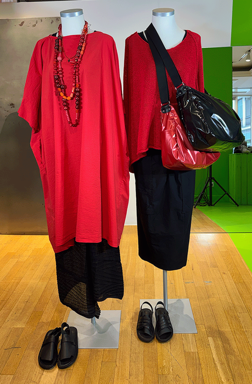 Zwei Mannequins mit roten Overdresses, schwarzer Kleidung und Accessoires auf Display.